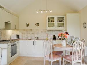 a kitchen with white cabinets and a table with chairs at Moorland Lodge in Chalbury