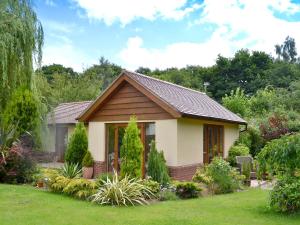 a small house in a garden with trees at Moorland Lodge in Chalbury