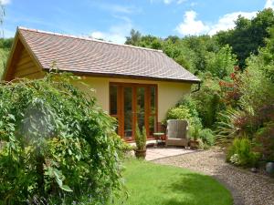 a small cottage in a garden with a patio at Moorland Lodge in Chalbury