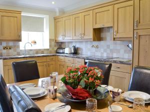 a kitchen with a table with a vase of flowers on it at 5 Pengraig Draw in Llanychaiarn