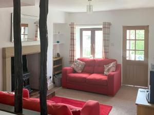 a living room with a red couch and a fireplace at Rock Cottage in Crosthwaite