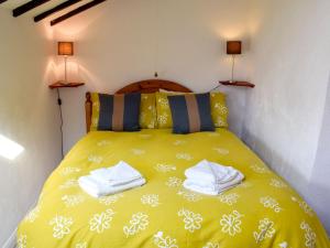 a bedroom with a yellow bed with towels on it at Rock Cottage in Crosthwaite
