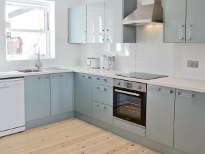 a white kitchen with white cabinets and an oven at Coastguard Cottage in Chestfield