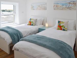 two twin beds in a room with a window at Coastguard Cottage in Chestfield