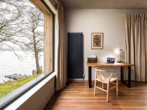 a desk and a chair in a room with a large window at Carsaig in Port of Menteith