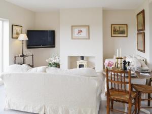 a living room with a white couch and a tv at Snooty Fox Cottage in Hexham