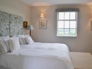 a bedroom with a large white bed with a window at Snooty Fox Cottage in Hexham