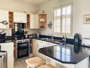 a kitchen with white cabinets and a black counter top at Snooty Fox Cottage in Hexham