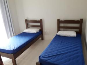2 Betten in einem Zimmer mit blauer Bettwäsche in der Unterkunft Casa em Costazul - Rio das Ostras in Rio das Ostras