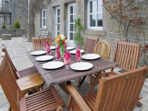 a wooden table with chairs and plates and flowers on it at Low Mill Cottage in Grassington