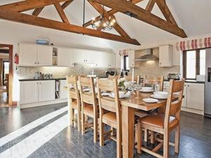 a kitchen with a wooden dining room table and chairs at Woodpecker Barn - Cwl in Sculthorpe