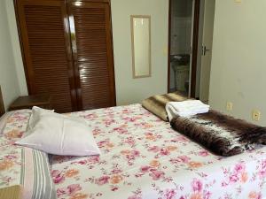 a bedroom with a bed with a flower patterned blanket at Apartamento 3 quartos Beira Mar in Anchieta