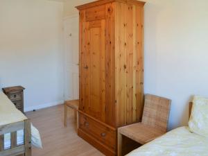 ein Schlafzimmer mit einem Holzschrank und einem Stuhl in der Unterkunft Smugglers Retreat in Woodhorn