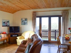 a living room with a leather couch and a balcony at Ithon Bank - Hw7478 in Penybont