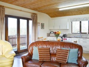 a leather couch in a living room with a kitchen at Ithon Bank - Hw7478 in Penybont