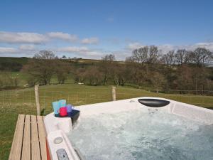 a hot tub in a yard with a wooden bench at Ithon Bank - Hw7478 in Penybont
