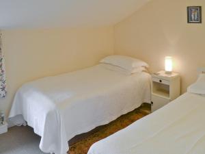 a bedroom with two beds and a lamp on a night stand at Varley House in Saxmundham