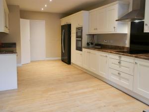 a kitchen with white cabinets and a wooden floor at Perch Hall Cottage in Dinwoodie Mains