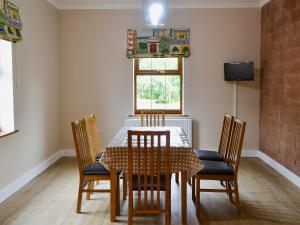 a dining room with a table and chairs and a window at Perch Hall Cottage in Dinwoodie Mains