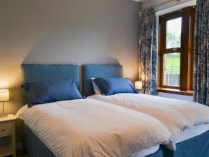 a bedroom with two beds with blue and white sheets at Perch Hall Cottage in Dinwoodie Mains