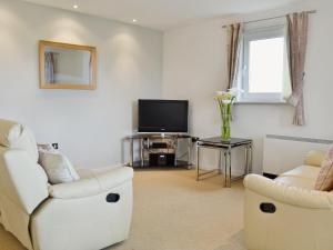 a living room with a white couch and a tv at Waters Edge in Llanelli