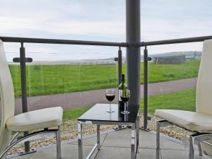 two glasses of wine sitting on a table on a balcony at Waters Edge in Llanelli