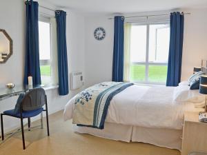 1 dormitorio con 1 cama con cortinas azules y escritorio en Waters Edge, en Llanelli