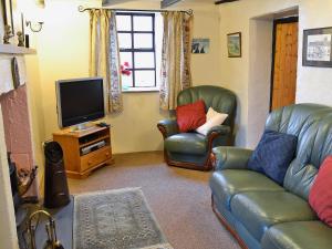 a living room with two leather chairs and a television at High Windy Cottage in Garrigill