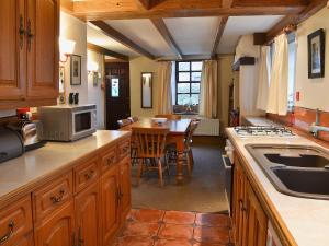 a kitchen with wooden cabinets and a table with a microwave at High Windy Cottage in Garrigill