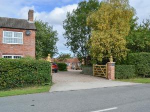 a brick house with a gate and a driveway at Wisteria Cottage - E5094 in Chapel Saint Leonards