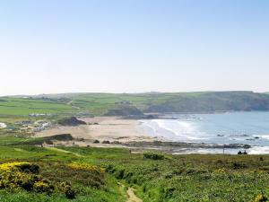 uma vista para a praia e para o oceano a partir de uma colina em Stonechat Barn em Pancrasweek