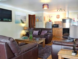 a living room with leather couches and a table at The Lodge in Brandesburton