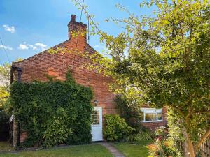 a red brick house with a white door at April Cottage in Frostenden