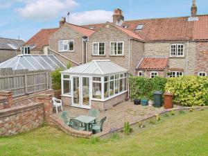a garden with a greenhouse in front of a house at No 2 Flowery Bank in Malton
