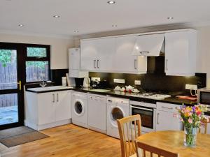 a kitchen with white cabinets and a wooden table at Riverside in Carlyon Bay