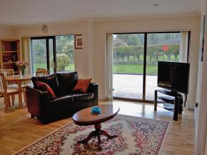 uma sala de estar com um sofá, uma mesa e uma televisão em Riverside em Carlyon Bay