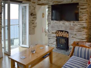 a living room with a fireplace and a tv on a stone wall at Seacharm in Gorran Haven