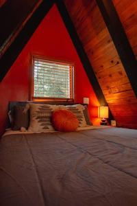 Bett in einem roten Zimmer mit Fenster in der Unterkunft Epic view A-frame - Hot-tub, Firepit, & Fireplace in Granite Falls