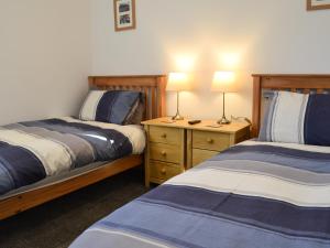 a bedroom with two beds and two lamps on night stands at The Granary in Criccieth