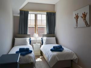 シェリンガムにあるMagnolia Lodgeのベッドルーム1室(青いタオル付きのベッド2台付)