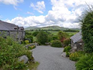a garden with a stone house and a gravel driveway at The Granary in Criccieth