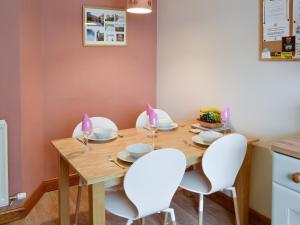 a dining room with a wooden table and white chairs at Wickhams View in Keswick