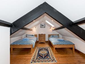 a attic room with two beds and a rug at The Old Bothy in Watermillock
