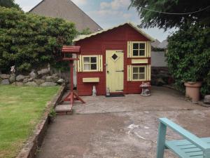 a red shed with a yellow door in a yard at Casa Nostro - 27825 in Wooler