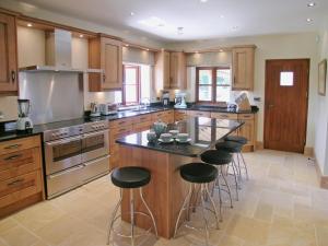 a kitchen with wooden cabinets and a island with bar stools at Orchard House in Parkham
