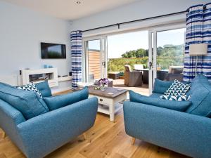 a living room with blue furniture and a sliding glass door at Dunlin 4 - The Cove in Brixham