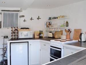 uma cozinha com armários brancos e um forno com placa de fogão em Chy An Ky Bras em Porthallow