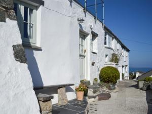 a white building with windows and plants on a street at Chy An Ky Bras in Porthallow