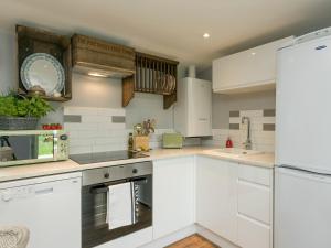uma cozinha branca com armários e electrodomésticos brancos em Barn Owl Lodge em Stoke Holy Cross