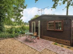 a small black shed with a patio and a table at Barn Owl Lodge in Stoke Holy Cross